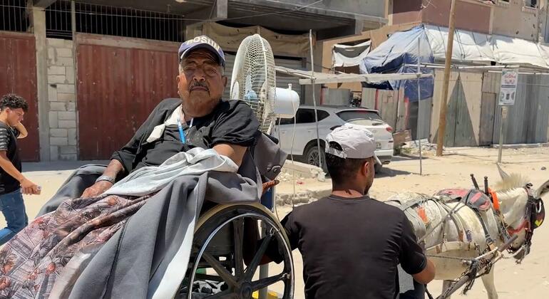 رجل فلسطيني مسن على كرسي متحرك يجلس على عربة يجرها حمار في خان يونس، غزة، أثناء نقله إلى مركز غسيل الكلى.