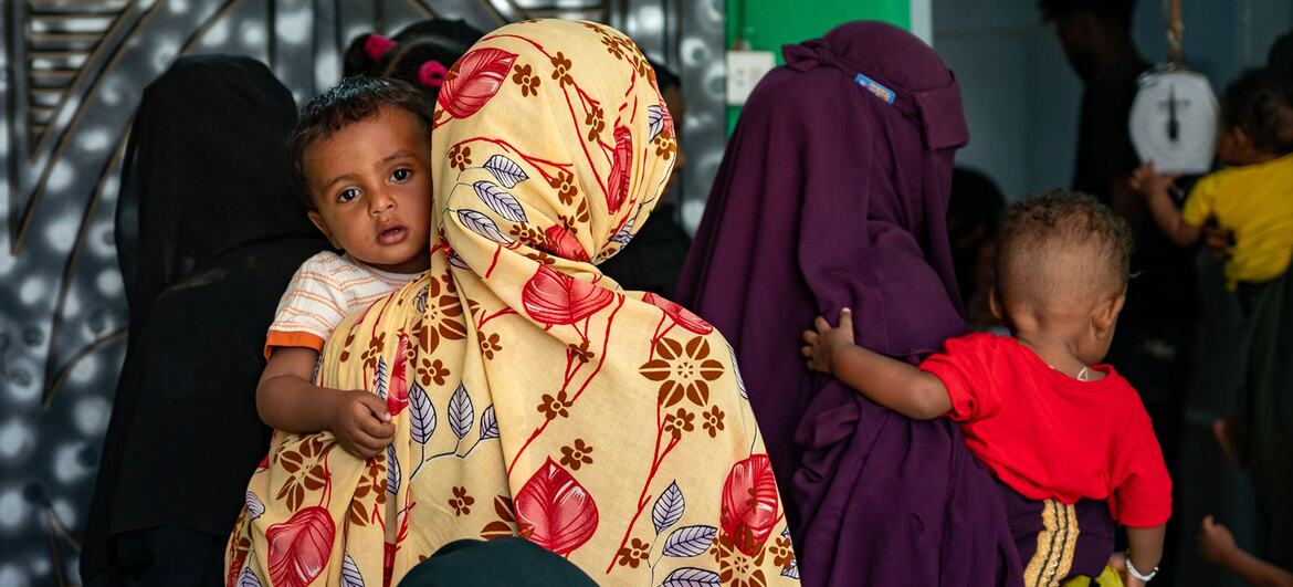 Mães aguardam atendimento para vacinação em um centro de saúde no estado de Kassala, Sudão, com crianças pequenas sob seus cuidados.