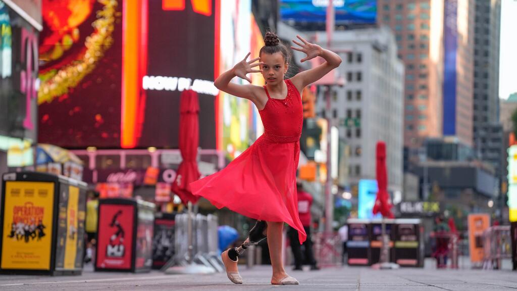 Une jeune fille ukrainienne vêtue d'une robe rouge exécute une danse dans une rue de la ville, à l'aide d'une prothèse de jambe.