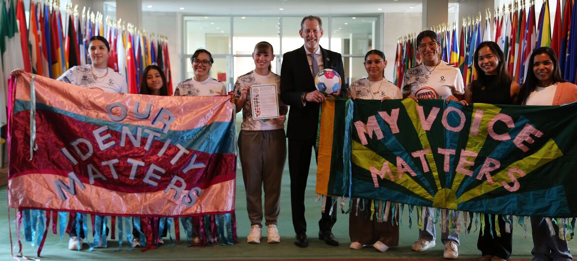 Robb Skinner stands with members of Street Child United at a UN event, holding banners that read 'Our Identity Matters' and 'My Voice Matters'.