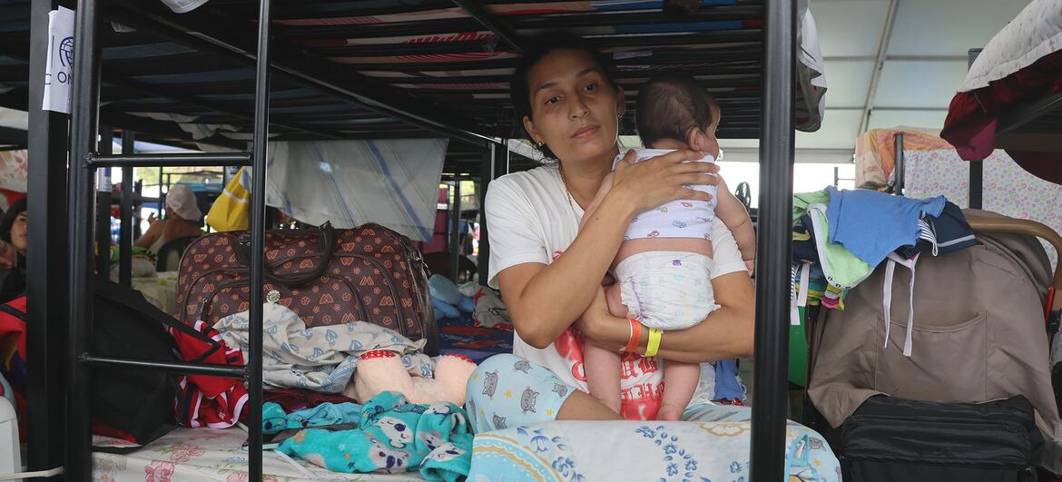 Uma mulher segura seu bebê enquanto está sentada em um beliche em um acampamento temporário para sobreviventes do terremoto na Venezuela.