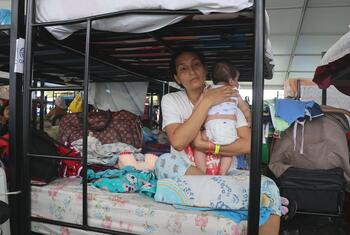 Una mujer sostiene a su bebé mientras está sentada en una litera en un campamento provisional para damnificados por el terremoto en Venezuela.