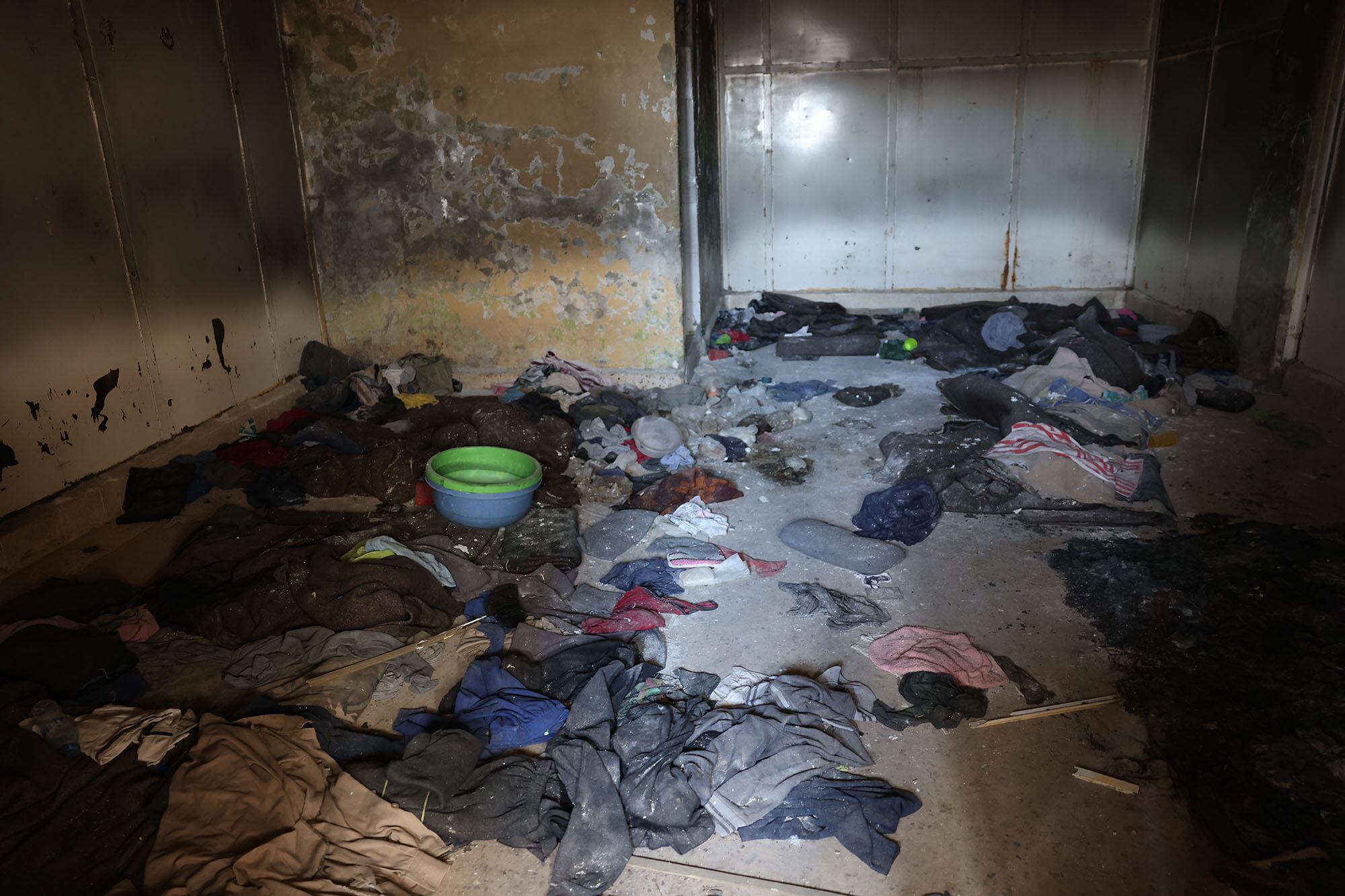 A view inside a cell at Sidnaya Prison in Syria, showing a floor littered with clothes and debris.