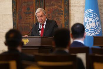 UN Secretary-General António Guterres speaks at a podium during a meeting, with the UN flag visible in the background.