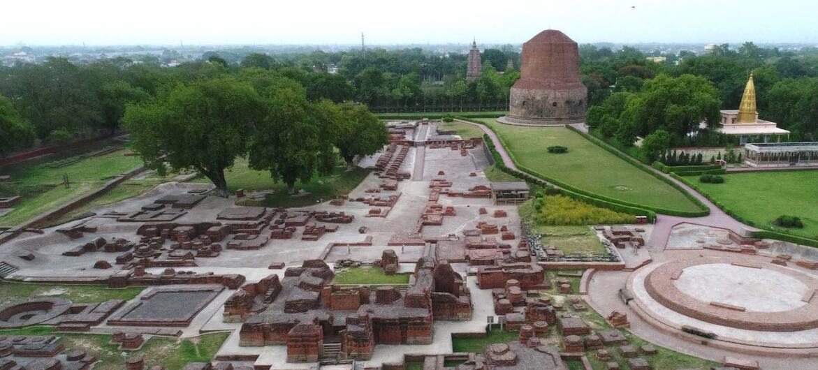 भारत में स्थित UNESCO विश्व धरोहर स्थल सारनाथ का हवाई दृश्य, जिसमें प्राचीन मठ और विशाल स्तूप के पुरातात्विक अवशेष दिखाई दे रहे हैं.
