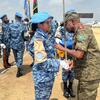 Mlinda amani UN wa kike kutoka Bangladesh aliyevaa sare ya bluu akipokea medali kutoka kwa afisa wa kiume aliyevaa mavazi ya kujificha kwenye uwanja wa ndege.
