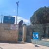 UNRWA Kalandia ٹریننگ سینٹر کے داخلی دروازے کا بیرونی منظر جس میں مرکزی دروازے کے اوپر اڑتا ہوا UN نیلا جھنڈا ہے۔