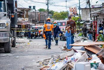 Emergency responders walk down a street filled with debris and rubble in the aftermath of a disaster in Colombia.