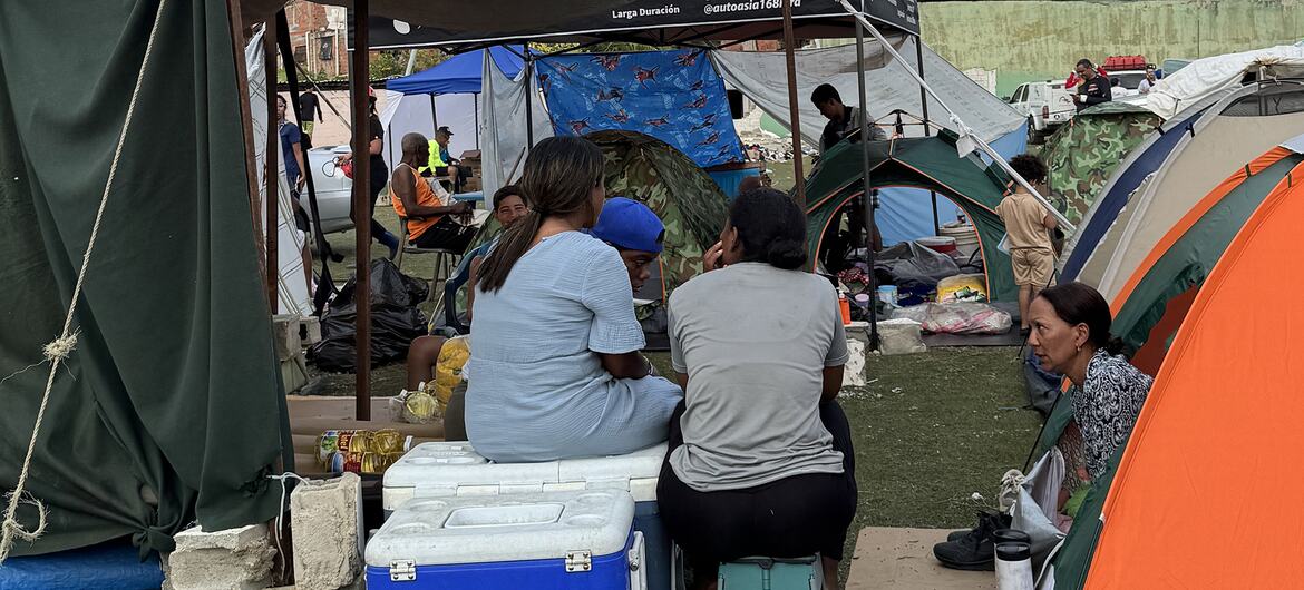 Las mujeres se sientan en un campamento provisional lleno de tiendas de campaña y refugios improvisados.