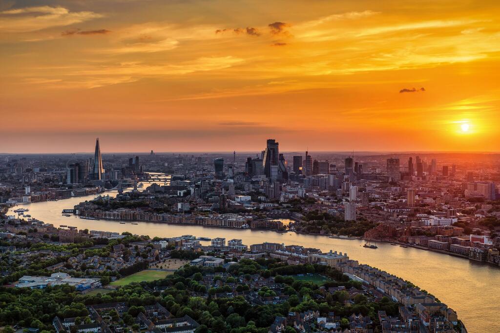 Mtazamo wa angani wa anga ya London wakati wa machweo huku Mto Thames ukipita katikati ya jiji.