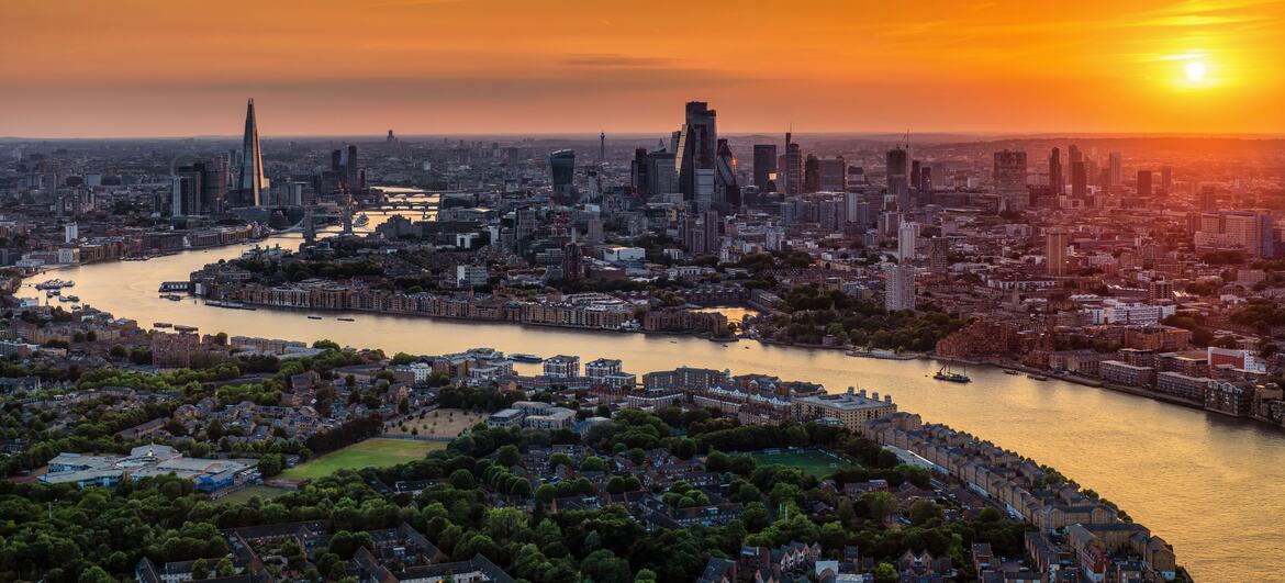 Aerial view of the London skyline at sunset with the River Thames flowing through the city.