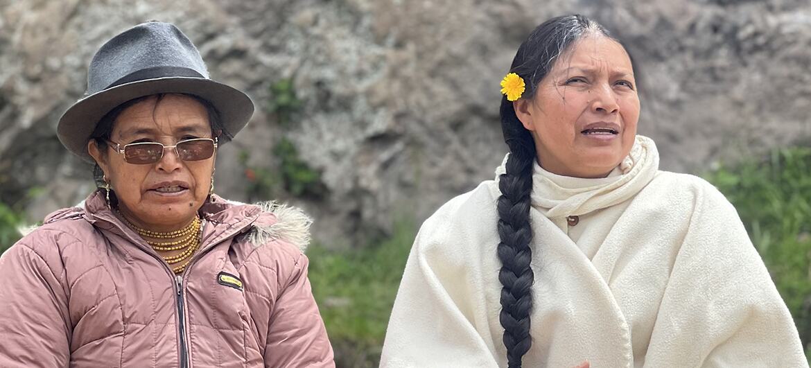 Dos mujeres ecuatorianas con atuendos tradicionales se sientan al aire libre para una ceremonia.