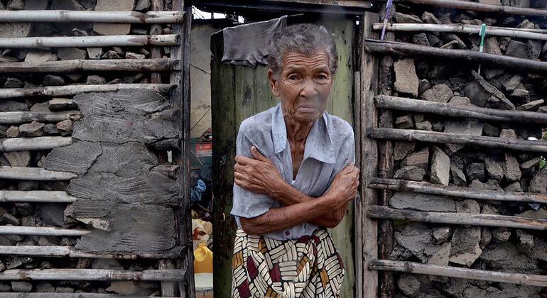 Uma senhora idosa está de braços cruzados em frente a uma casa severamente danificada após a passagem do ciclone em Beira, Moçambique.
