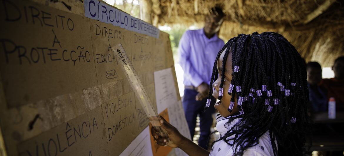 Uma jovem africana aponta para um cartaz durante uma sessão de círculo de interesse sobre a proteção de jovens e crianças na Escola de Chibava, em Moçambique.