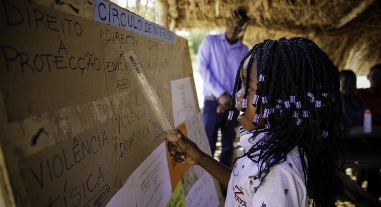Uma jovem africana aponta para um cartaz durante uma sessão de círculo de interesse sobre a proteção de jovens e crianças na Escola de Chibava, em Moçambique.