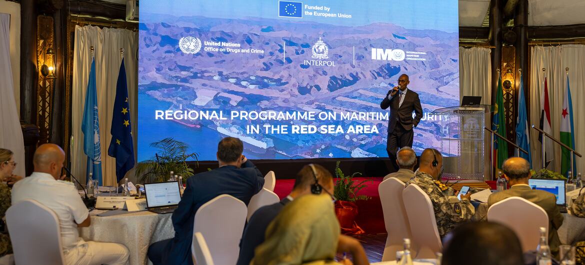 Speaker addresses delegates at the 5th Regional Maritime Law Enforcement Dialogue for the Red Sea and Gulf of Aden in Nairobi; screen shows UNODC, INTERPOL, IMO and EU logos.