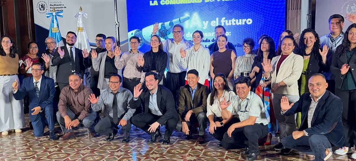 Un numeroso grupo de aproximadamente 30 profesionales posa junto en un evento en interiores. Detrás de ellos, una pantalla azul muestra «LA COMUNIDAD DE PRÁCTICA» e «IA y el futuro», y en una pancarta lateral se aprecian los logotipos del UNDP y del Ministerio de Administración Pública.