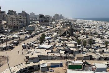 Vue aérienne d'un immense campement de tentes et de bâtiments endommagés le long du littoral de la bande de Gaza, près de la mer Méditerranée.