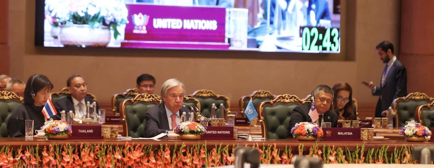 Le secrétaire général de ONU, António Guterres, apparaît sur un grand écran et prononce un discours virtuel lors du sommet des BRICS en Inde, tandis que des délégués de Thaïlande et de Malaisie sont assis à la table principale.