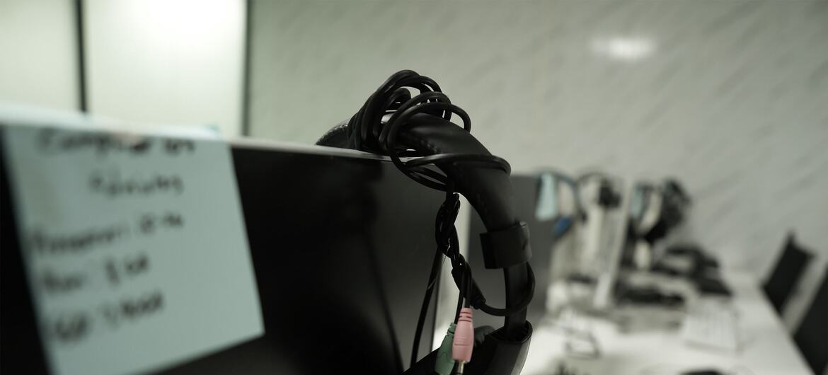 A black headset with a microphone rests on top of a computer monitor in an office setting.