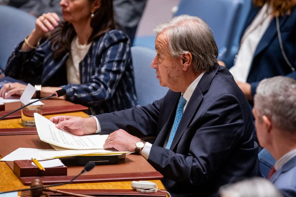 Le secrétaire général de ONU, António Guterres, lit des documents officiels, assis à une table du Conseil de sécurité lors d'une réunion des Nations Unies .