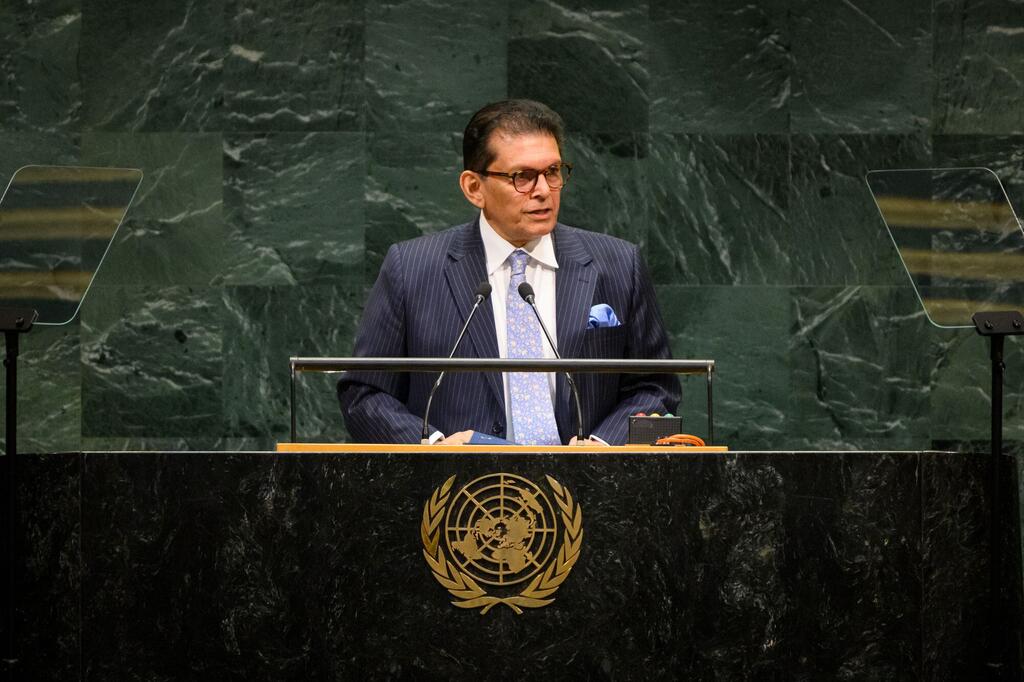 Le président de l'Assemblée générale des ONU , Khalilur Rahman, prend la parole à une tribune munie de microphones, devant un mur de marbre vert.