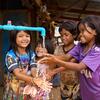 Quatre jeunes filles Jarai, de la communauté autochtone, se lavent les mains sous un robinet à tuyau bleu dans un village rural de la province de Ratanakiri, au Cambodge.