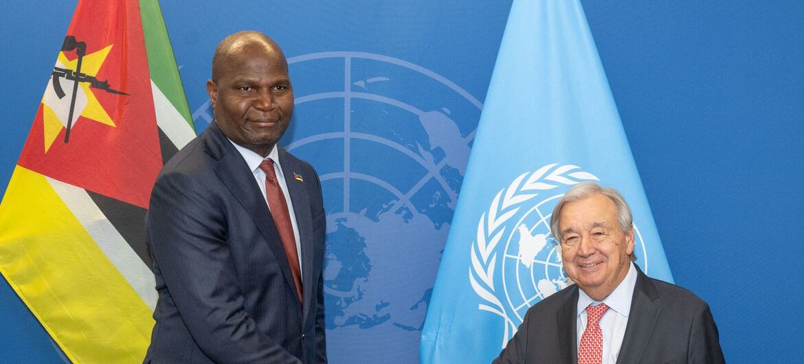 O presidente moçambicano Daniel Chapo cumprimenta o secretário-geral das Nações Unidas em frente às bandeiras de Moçambique e da ONU , tendo como pano de fundo o azul da ONU .