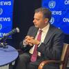 Durante uma entrevista, Luis Montenegro está sentado a uma mesa com um microfone de estúdio em frente a painéis azuis que exibem o texto da ONU News e emblemas das Nações Unidas .