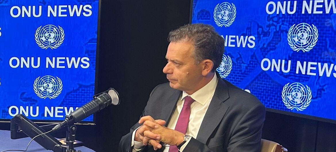 Durante uma entrevista, Luis Montenegro está sentado a uma mesa com um microfone de estúdio em frente a painéis azuis que exibem o texto da ONU News e emblemas das Nações Unidas .