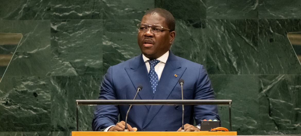 O primeiro-ministro da Guiné-Bissau, Ilídio Vieira Té, discursa em um pódio com o logotipo das Nações Unidas , vestindo um terno azul e óculos.