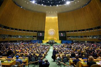 UN Secretary-General António Guterres speaks from a podium in the United Nations General Assembly Hall during the opening of the eighty-first session, with delegates seated and his image on two screens.