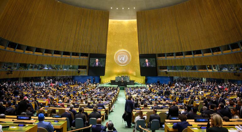 يتحدث الأمين العام الأمم المتحدة أنطونيو غوتيريش من على منصة في قاعة الجمعية العامة United Nations خلال افتتاح الدورة الحادية والثمانين، بينما يجلس المندوبون وتظهر صورته على شاشتين.