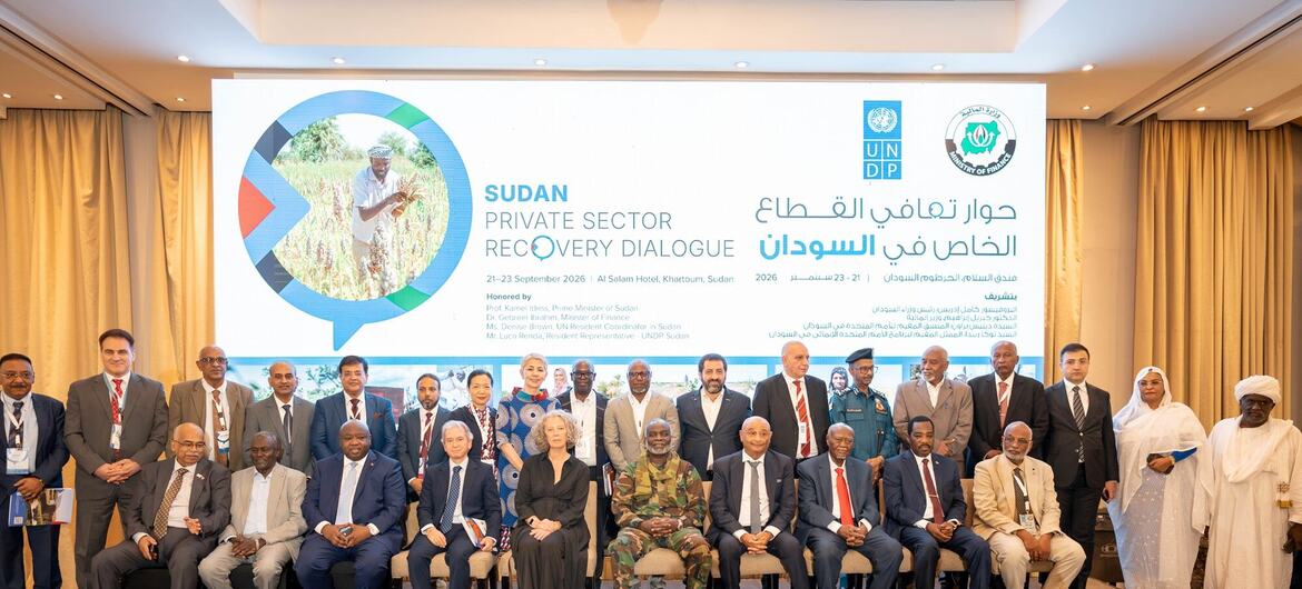 Group of Sudanese officials, business leaders, and a military officer pose on a stage before a UNDP Sudan Private Sector Recovery Dialogue backdrop at Al Salam Hotel in Khartoum.