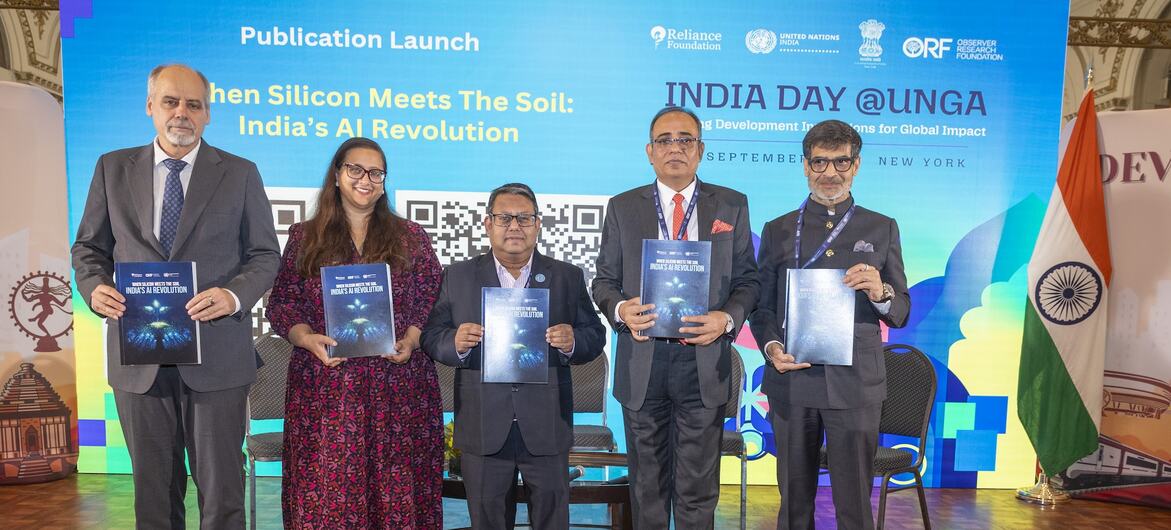 न्यूयॉर्क में संयुक्त राष्ट्र महासभा के भारत दिवस कार्यक्रम में एक मंच पर पांच लोग, जिनमें चार भारतीय पुरुष और एक भारतीय महिला शामिल हैं, एक प्रकाशन की प्रतियां पकड़े हुए हैं, और दाईं ओर एक भारतीय ध्वज है।
