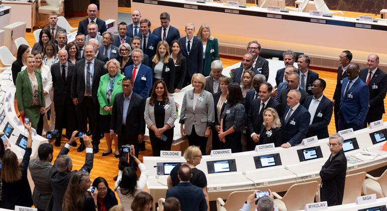 2026 کے میئرز فورم کے دوران رسمی لباس میں میئرز اور سٹی آفیشلز کا گروپ United Nations سلامتی کونسل کے چیمبر میں تصویر کے لیے پوز دے رہا ہے، فوٹوگرافرز اس لمحے کو قید کر رہے ہیں۔