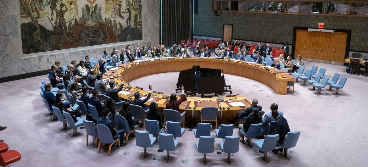 UN Security Council delegates seated around the horseshoe table in the New York chamber raise hands during a vote on Resolution 2831 (2026) concerning Haiti.