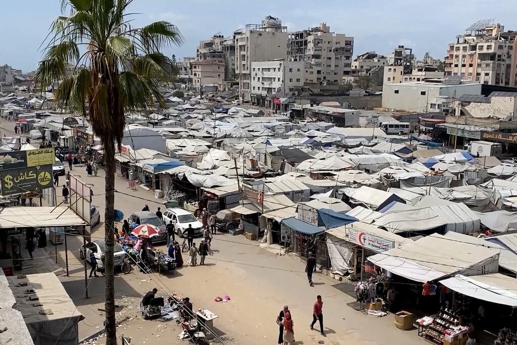 Des abris de toile occupent une place publique du quartier Rimal de la ville de Gaza, les habitants se déplaçant entre les étals situés près des bâtiments endommagés.