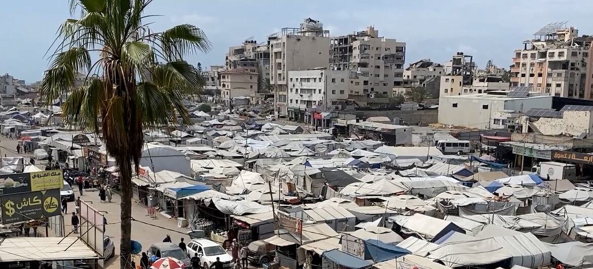 Canvas shelters occupy an open square in Gaza City's Rimal neighbourhood, with residents moving among stalls near damaged buildings.