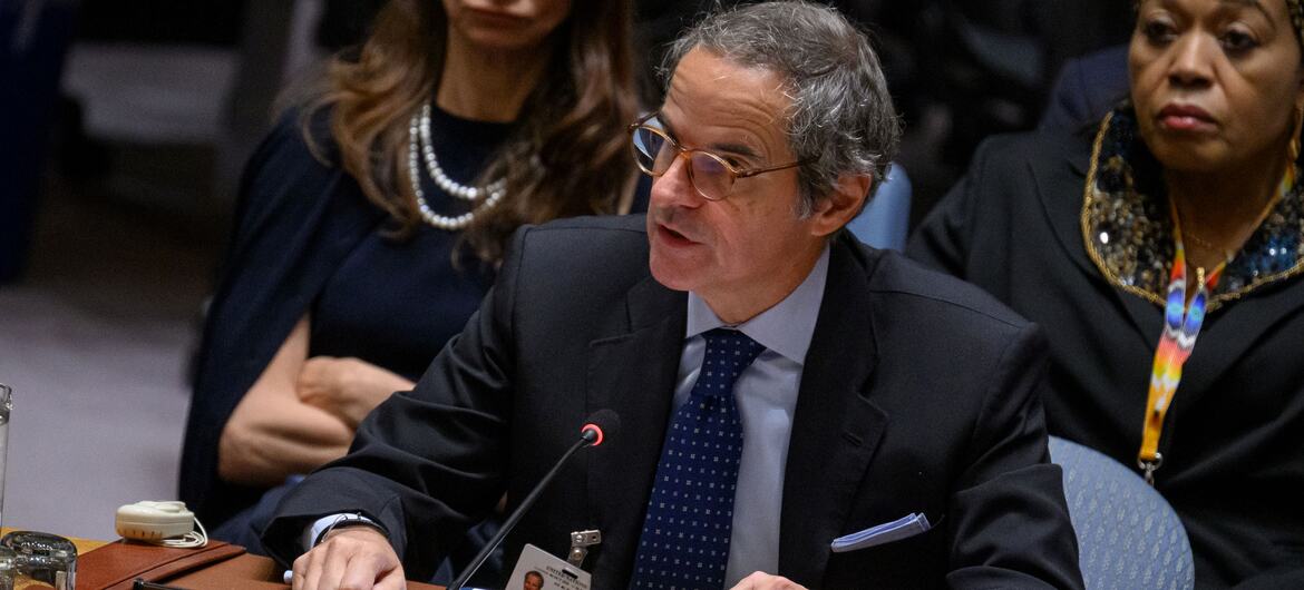 Rafael Mariano Grossi speaks at a United Nations Security Council table with an International Atomic Energy Agency placard, while two women listen behind him.