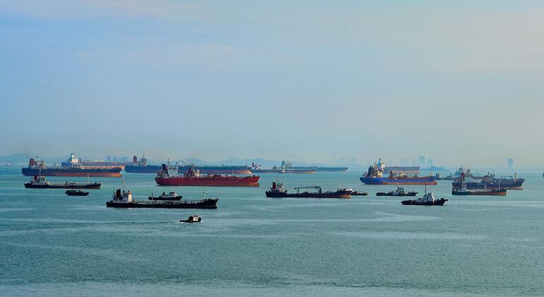 De nombreux cargos, pétroliers et remorqueurs naviguent dans les eaux calmes du détroit de Malacca sous un ciel brumeux.