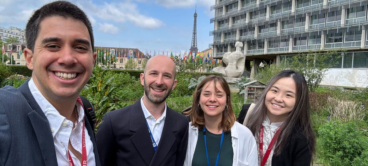 ASG Felipe Paullier and Romain Parlier with youth in Beirut, standing outdoors near the Eiffel Tower and a modern building, smiling for a photo.