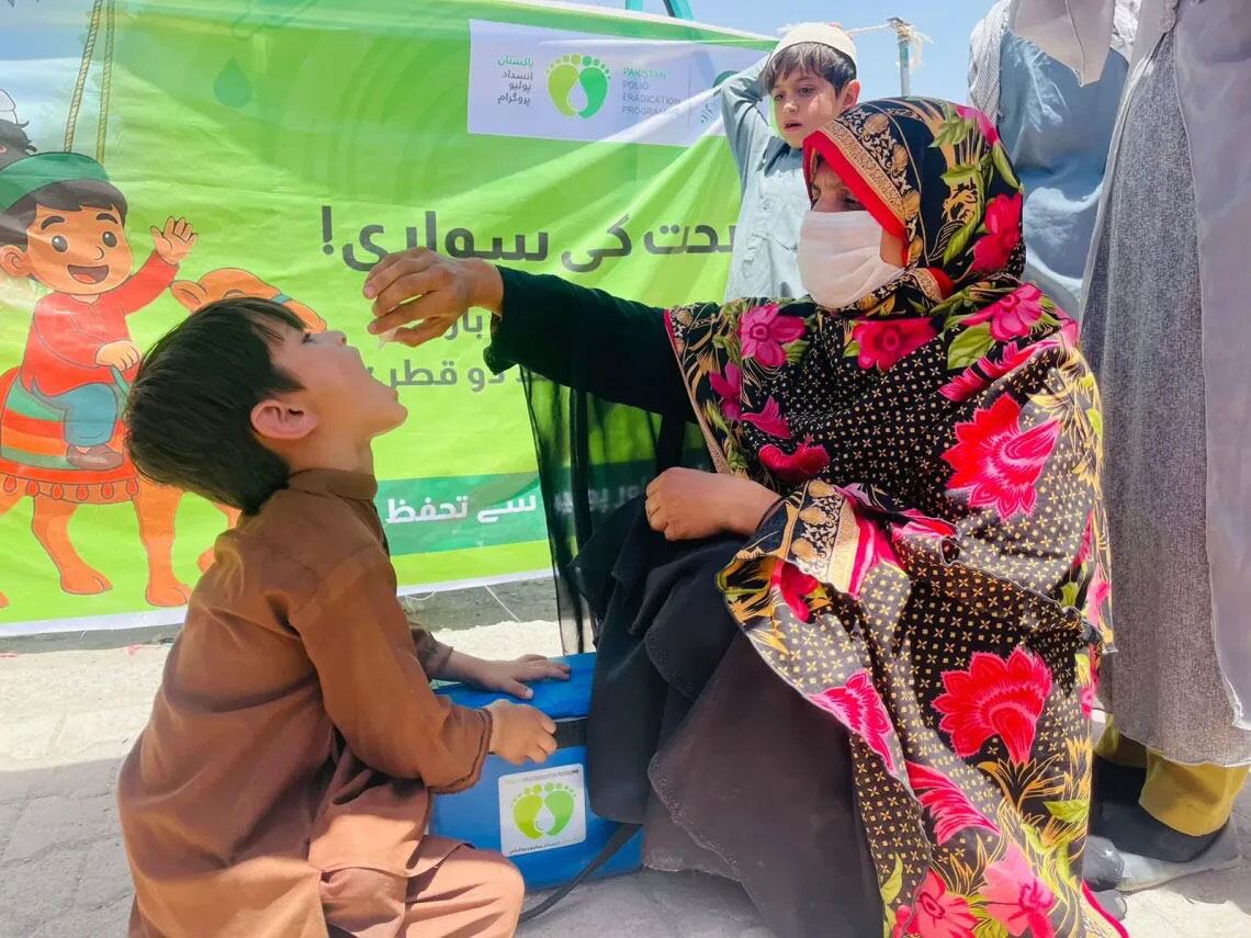 جاپان کی حمایت یافتہ یونیسف کے امیونٹی ایکسپریس پروگرام کے تحت ایک ہیلتھ ورکر نے بلوچستان، پاکستان میں ایک نوجوان لڑکے کو پولیو ویکسین دی۔ بچے کی ماں ماسک پہن کر قریب سے دیکھ رہی ہے۔