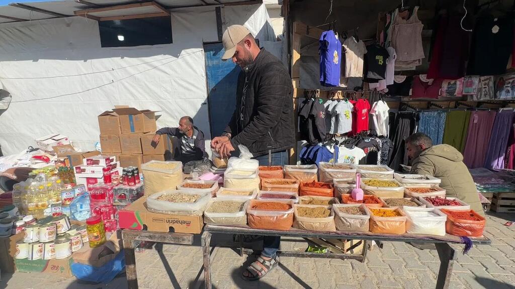 Wanaume wa Kipalestina wauza mizigo ya kipeo, bidhaa kavu, na nguo kutoka maduka ya soko la muda huko Khan Younis, Gaza.