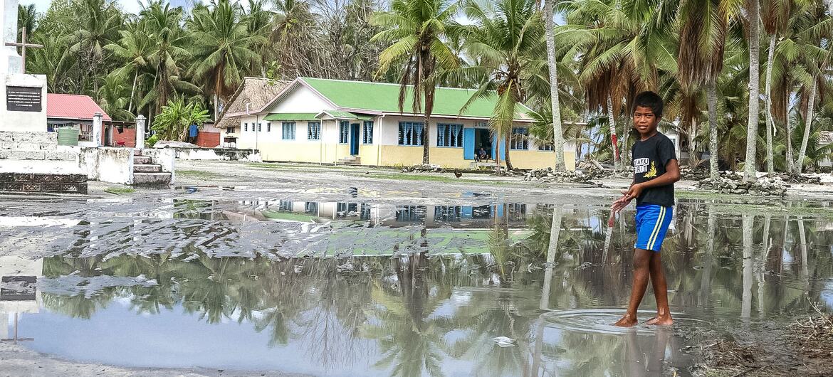 A young Pacific Islander boy walks through floodwaters at the main square on the island of Nui, Tuvalu, after Cyclone Pam caused widespread destruction and coastal erosion more than a month ago.