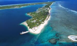 Aerial view of the island nation of Tuvalu showing its narrow strip of land surrounded by a vibrant turquoise lagoon and deep blue ocean, highlighting the effects of coastal erosion and climate change.