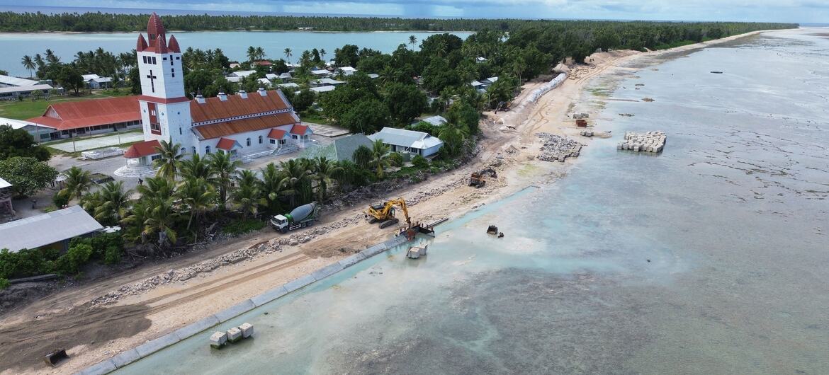 Security, sacrifice or opportunity: Visions differ over effective climate action 1 Aerial view of a coastal construction site in Tuvalu with a white church in the background. Heavy machinery is working on the beach near the water's edge to combat coastal erosion.