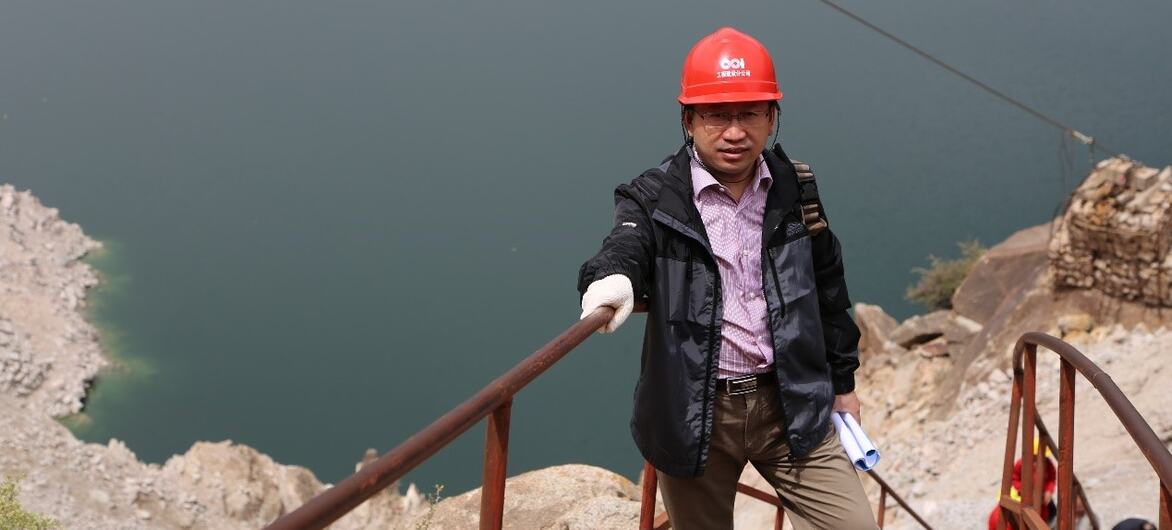一位戴着红色安全头盔的工程师站在CREEI清洁能源设施的一个大型水库的金属楼梯上.