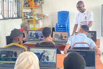 Os estudantes da Tanzânia participam de uma aula de educação em TIC, usando laptops e guiados por um professor em um ambiente de laboratório informático.