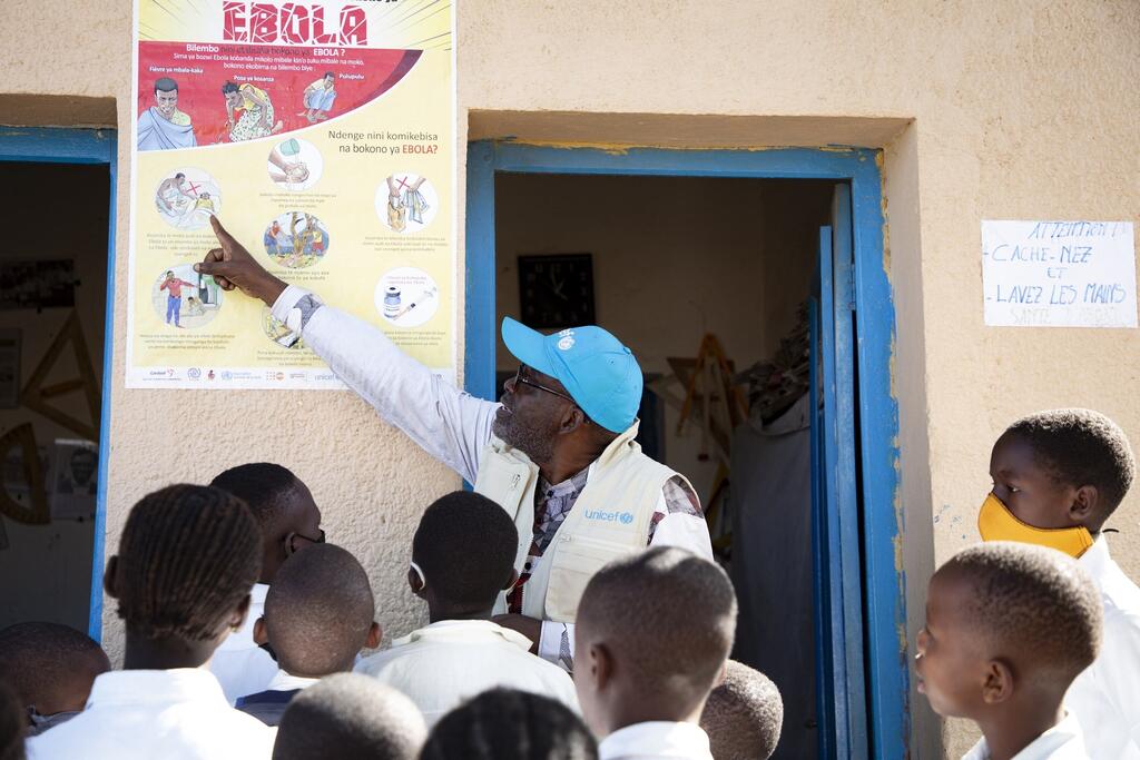 UNICEF WASH Officer Ciza Nyalundja explains Ebola prevention measures to pupils at a school in Bunia, Ituri Province, DR Congo.